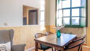 A dining area with a wooden table, chairs, and a vase with flowers. - 4BR w/ 200yrs of history in Porto by LovelyStay (Porto)