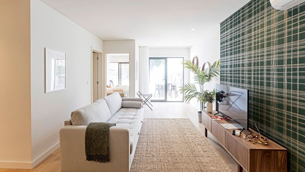 A modern living room with a sofa, a TV on a wooden stand, and a green patterned wall. - Paraíso -1B w/ AC & Patio by LovelyStay (Porto)