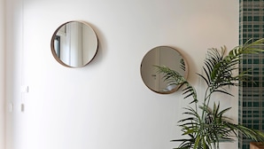 Two round mirrors on a white wall, a potted plant, and a green patterned fabric. - Paraíso -1B w/ AC & Patio by LovelyStay (Porto)