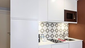Una cocina compacta con microondas, pileta y un salpicadero con diseño.