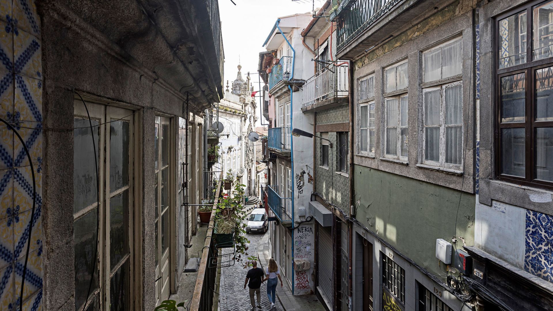 Une rue étroite, bordée de bâtiments des deux côtés, qui se distingue par son architecture traditionnelle et son chemin pavé.