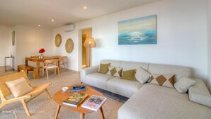 A living room with a sofa, coffee table, and a dining area with a table and chairs. - Bergerie, Panoramic sea view, Heated pool, Gr20 access (Sari-Solenzara)