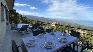 A dining table set for four with a view of the sea and mountains in the background. - Bergerie, Panoramic sea view, Heated pool, Gr20 access (Sari-Solenzara)