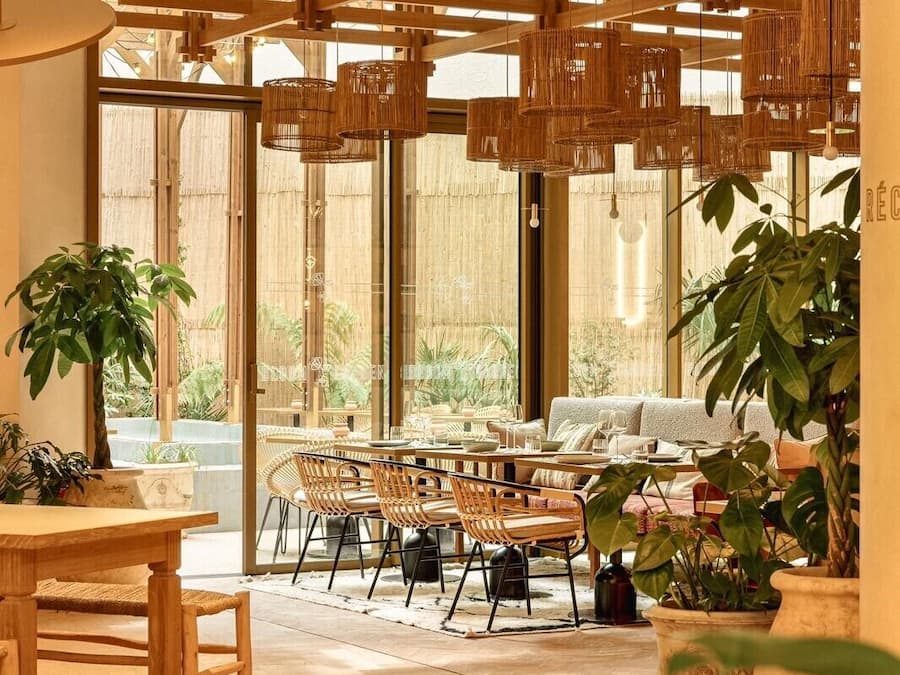 A modern interior with a dining area, large windows, and hanging wicker light fixtures.