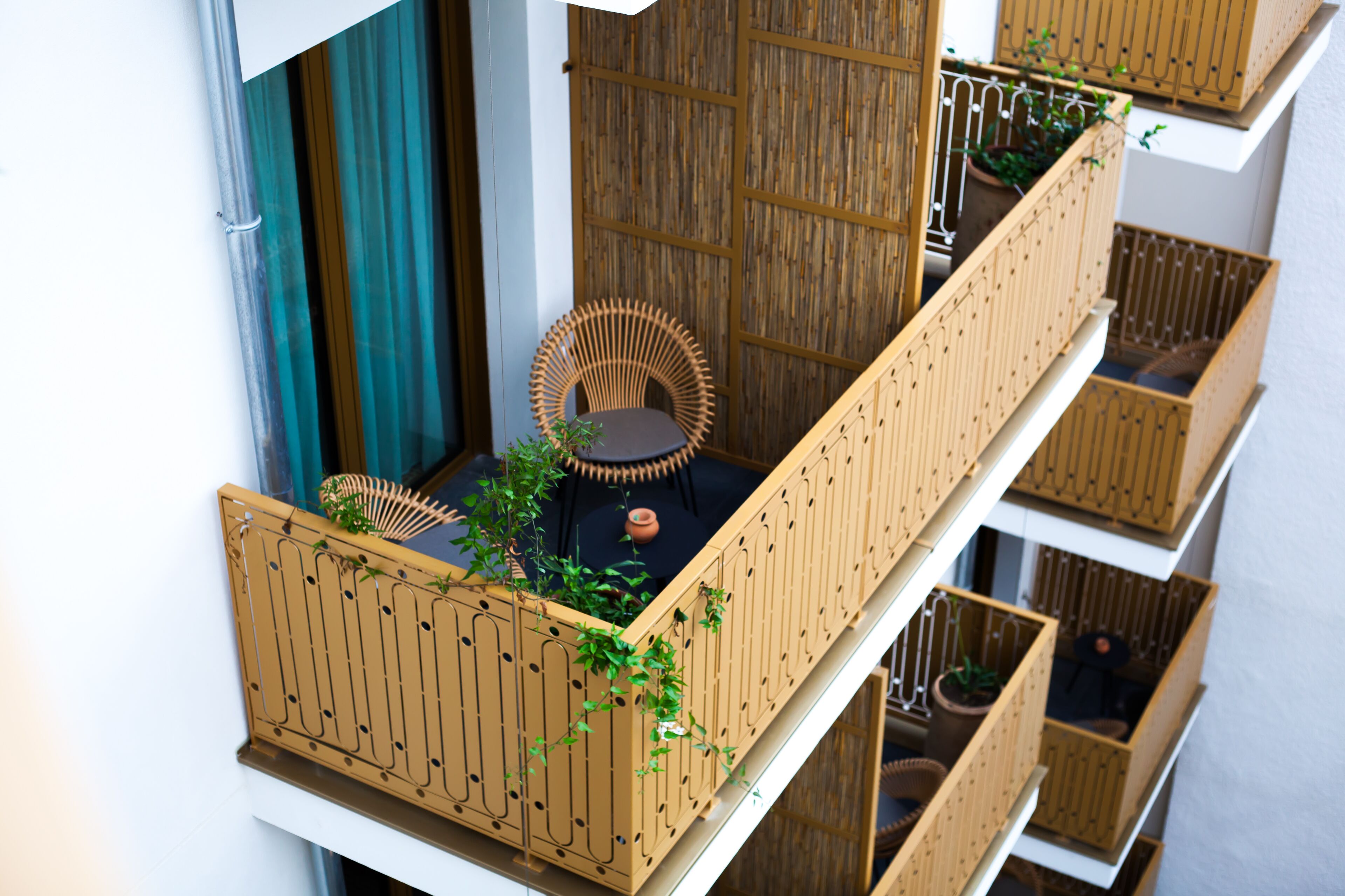 A balcony with a wicker chair, a small table, and potted plants.