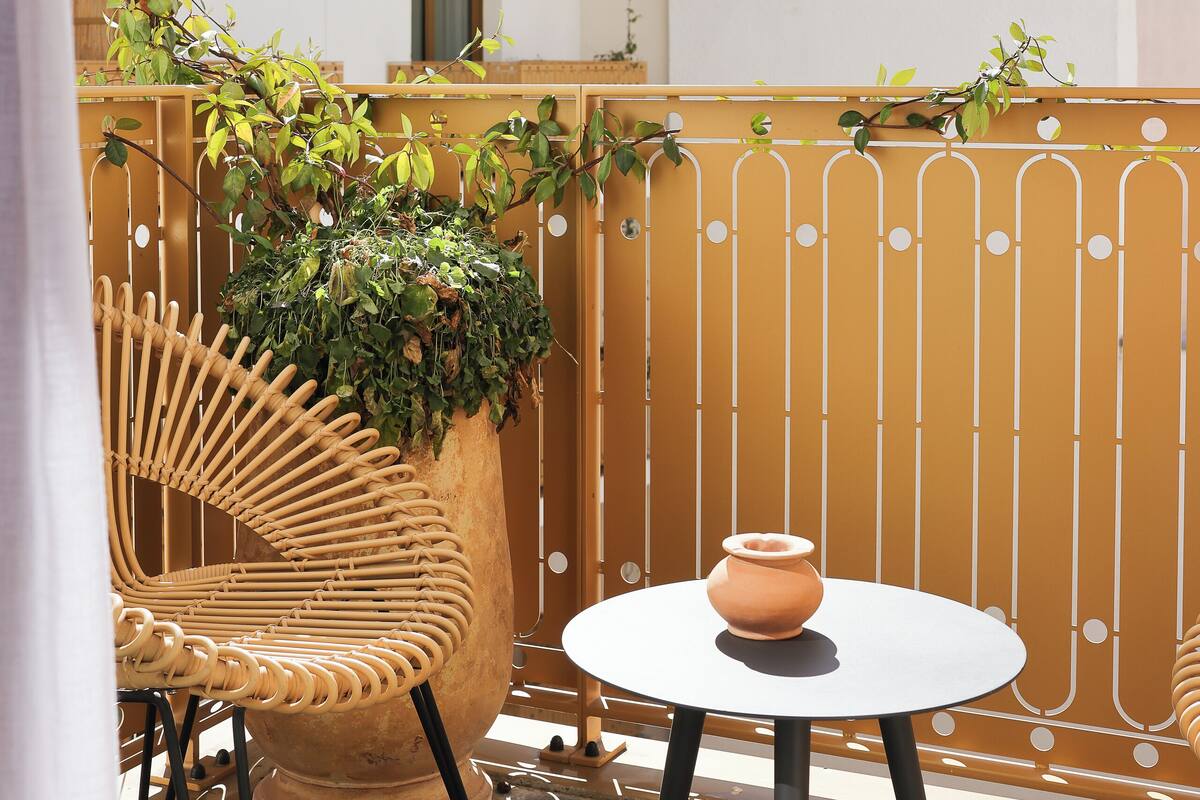 A balcony with wicker chairs, a round table, and a potted plant.