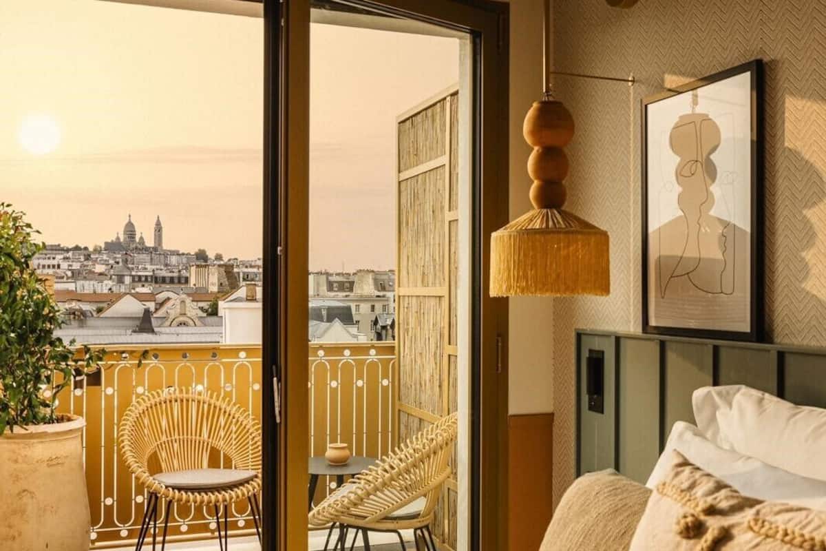 A hotel room with a balcony, a bed, and a city view.