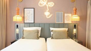 A hotel room with two beds, a neon flower wall art, and a framed picture.