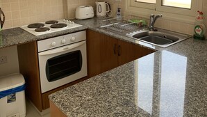 Une cuisine avec des meubles en bois, un fourneau blanc, un évier et une fenêtre donnant sur l’extérieur.