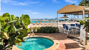 A pool area with lounge chairs and a covered seating area.