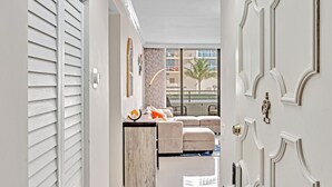 A hallway leading to a living area with a sofa, a small table, and a view of the outside.