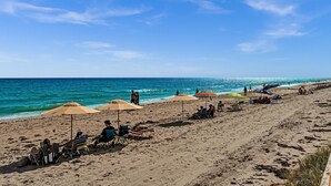 A beach with umbrellas, chairs, and people relaxing.