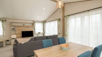 A modern living room with a sofa, a TV, and a dining table.