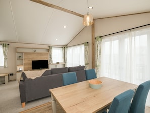 A modern living room with a sofa, a TV, and a dining table.