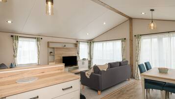A spacious living area with a sofa, dining table, and kitchen counter.