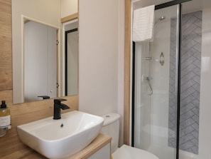 A modern bathroom with a white sink, a toilet, and a glass-enclosed shower.