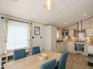 A modern kitchen with a wooden table, blue chairs, and a built-in oven.