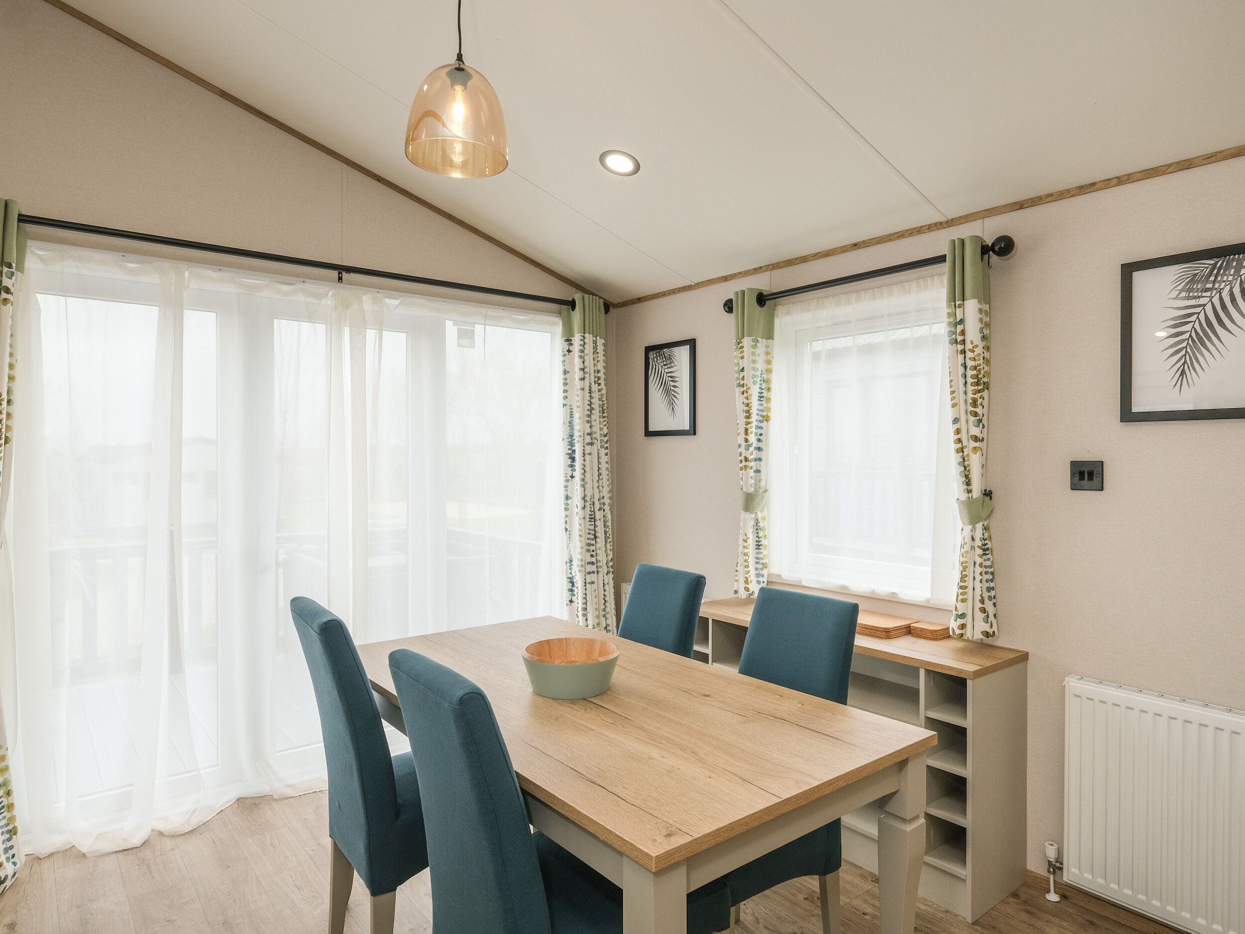A dining area with a wooden table, blue chairs, and a hanging pendant light.