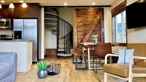 A modern living room with a wooden coffee table, a blue patterned rug, a sofa, and a dining area with a table and chairs. - Newly Updated, Cozy and Spacious Condo! (Frisco)