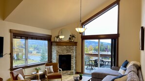 A spacious living room with a fireplace, large windows, and a balcony. - Newly Updated, Cozy and Spacious Condo! (Frisco)