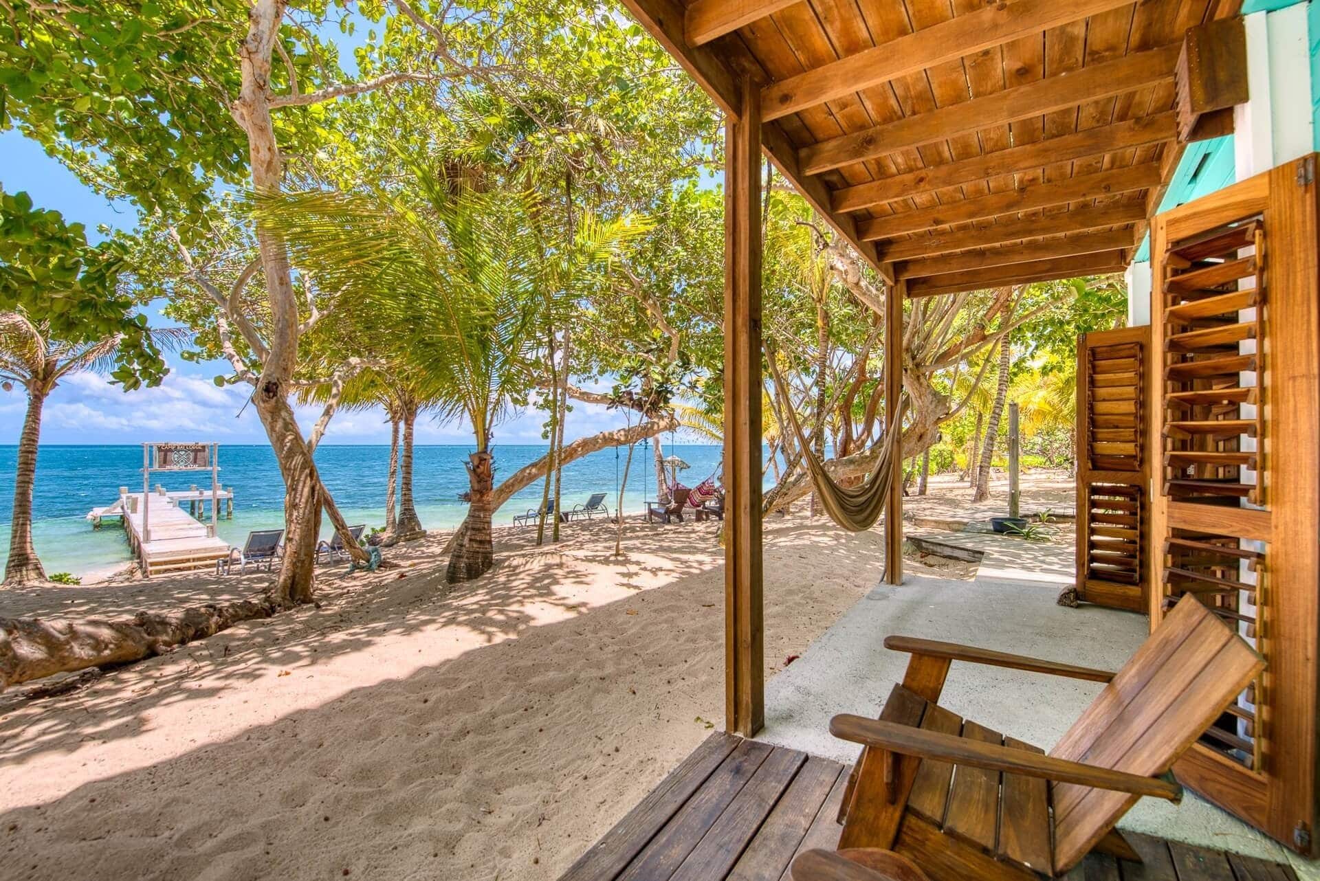 Eine Holzhütte am Strand mit Blick auf das Meer und Palmen.