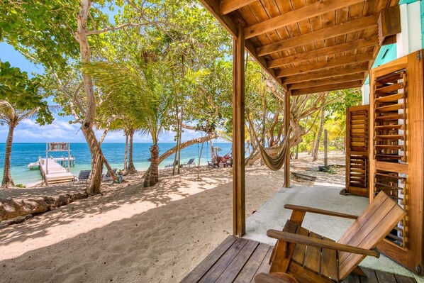 A wooden beach cabana with a view of the ocean and palm trees.