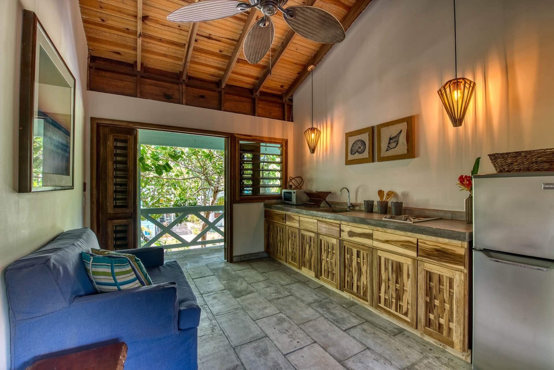 A cozy kitchen with wooden cabinets, a built-in refrigerator, and a dining area with a blue sofa.