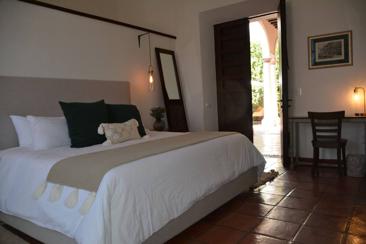 A bedroom with a bed, a desk, and a chair.