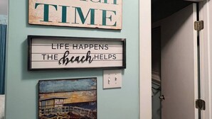 A wall with a sign that reads "BEACH TIME" and another sign below it stating "LIFE HAPPENS THE beach HELPS".