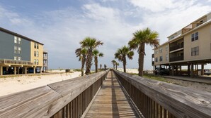 A wooden boardwalk leading to beachside buildings with balconies. - Two 2BD/2BA 1st floor Condos for Group/Family/Sports Team Vacation (Gulf Shores)