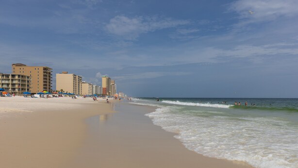 A beach with a sandy shore, waves, and buildings in the background. - Two 2BD/2BA 1st floor Condos for Group/Family/Sports Team Vacation (Gulf Shores)