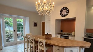 A modern kitchen with a wooden island, white cabinetry, and a large clock on the wall. - Stunning and Luxurious Manor House Holiday Home (Dorchester)