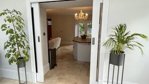 An open doorway leading to a living area with a white sofa, a dining table, and a chandelier. - Stunning and Luxurious Manor House Holiday Home (Dorchester)