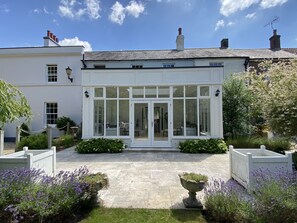 A traditional house with a conservatory, stone pathway, and lavender plants. - Stunning and Luxurious Manor House Holiday Home (Dorchester)