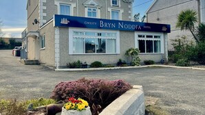 Ein zweistöckiges Hotel mit klassischer Architektur, mit einer auffälligen Schilderfassade, die den Namen 'Bryn Noddfa Hotel' trägt.