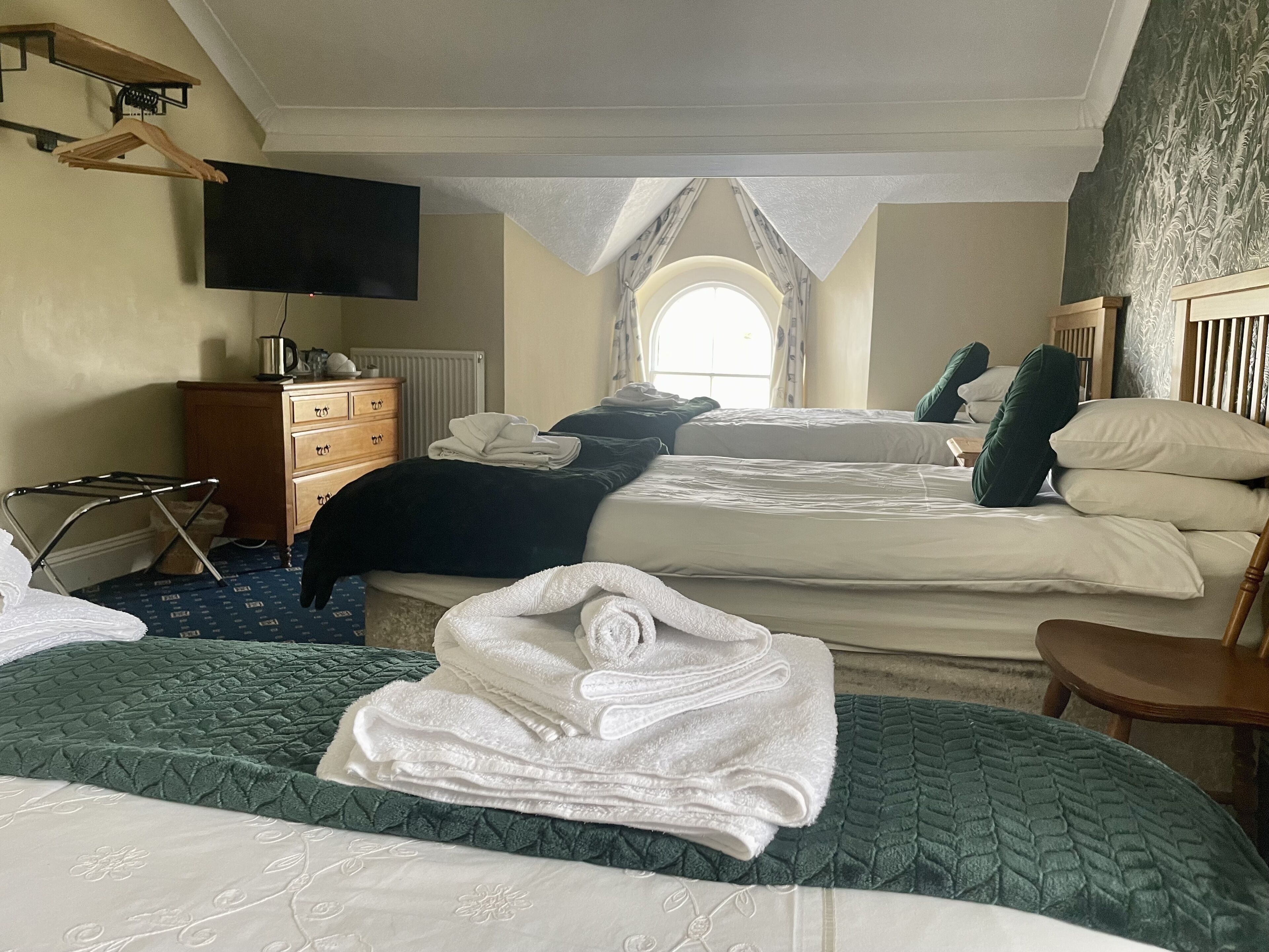 Een hotelkamer met twee bedden, een televisie, een houten dressoir en een raam met uitzicht.