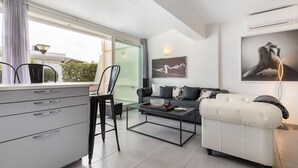 Ein modernes Wohnzimmer mit einer Couch, einem Couchtisch und einem Essbereich mit Stühlen und einem Schrank.