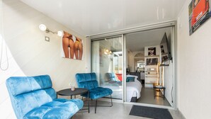 Ein modernes Hotelzimmer mit Balkon, einer Couch, einem kleinen Tisch und einem Bett.