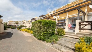Eine Wohnstraße mit Häusern, einer gepflasterten Straße und einer gepflegten Hecke.