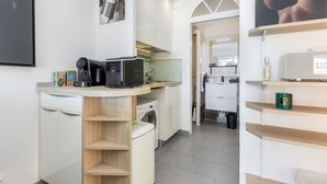 Eine kleine Küche mit Waschmaschine, Kaffeemaschine und Mikrowelle.