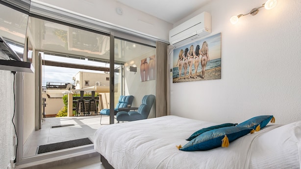 Ein Schlafzimmer mit einem großen Bett, einem Gemälde einer Strandansicht und Blick auf den Balkon.