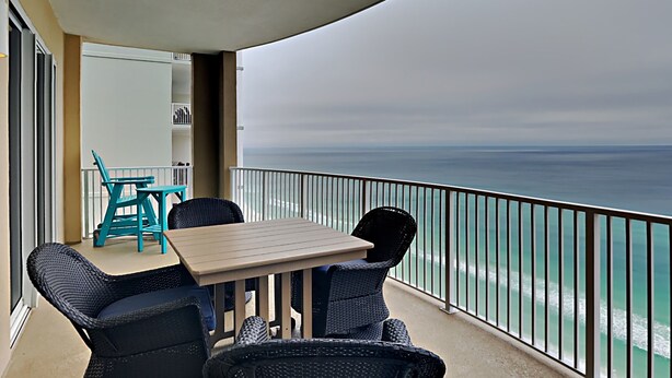 A balcony with a table and chairs, overlooking the ocean. - Ocean Villa #2106 by Resort Collection (Panama City Beach)