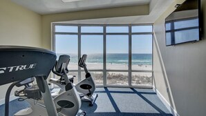 A gym with two treadmills and a large window overlooking the beach. - Ocean Villa #2106 by Resort Collection (Panama City Beach)