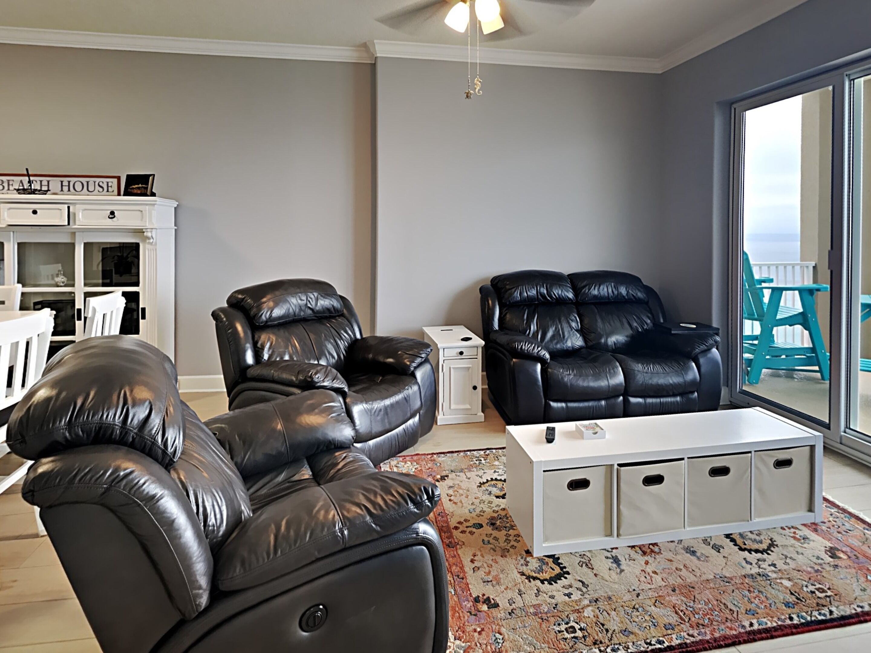 Ein Wohnzimmer mit einer schwarzen Ledersofa, einem weißen Couchtisch und einem gemusterten Teppich.