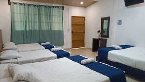 A hotel room with four beds, a wooden door, a TV, and a small desk with a lamp. - Hotel El Patio de Don Moncho (Santa Tecla)