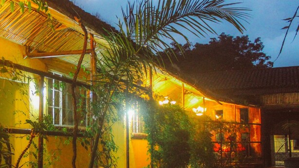 A traditional building with a thatched roof, surrounded by greenery and illuminated by warm lighting. - Hotel El Patio de Don Moncho (Santa Tecla)