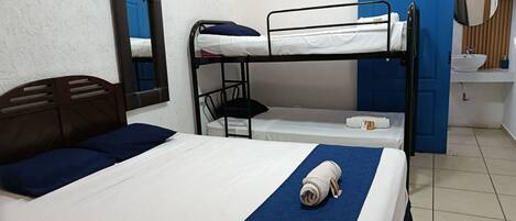 A bunk bed room with a single bed, a mirror, a sink, and a blue door.