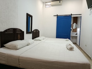 Quarto com cama, espelho, guarda-roupa e banheiro com pia.