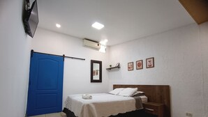 A bedroom with a bed, a blue door, an air conditioning unit, and a wall-mounted shelf with pictures. - Hotel El Patio de Don Moncho (Santa Tecla)
