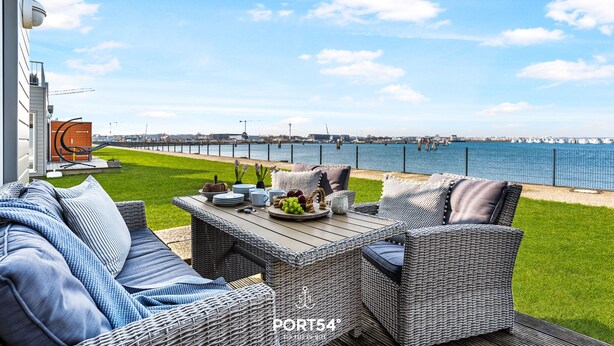 Een terras met rieten meubilair, een tafel met fruit en uitzicht op zee.